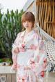 A woman wearing a white kimono standing in front of a hammock.