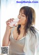 A woman in a bathrobe drinking from a bottle.