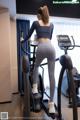 A woman is standing on a treadmills in a gym.