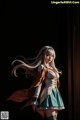 A woman with long white hair standing in front of a black background.