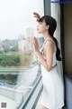 A woman in a white dress looking out a window.