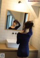 A woman standing in front of a mirror in a bathroom.