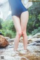 A woman in a blue bathing suit standing in a stream.