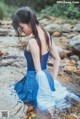 A woman in a blue dress is standing in a stream.