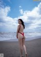 A woman in a red bikini standing on a beach.