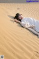 A woman laying on top of a sand dune.