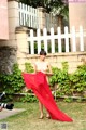 A woman in a red dress is standing in the grass.