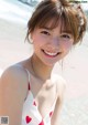 A woman in a white and red bathing suit on the beach.