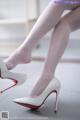 A close up of a woman's legs wearing white high heels.