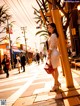 A woman in a white dress is walking down the street.