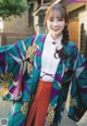 A woman wearing a colorful kimono standing in front of a building.