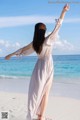 A woman standing on a beach with her arms outstretched.