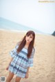 A woman standing on a sandy beach next to the ocean.