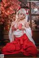 A woman in a red and white kimono sitting on a wooden floor.