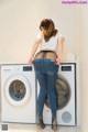 A woman standing in front of a washing machine.