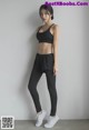 A woman in a black sports bra top and black leggings.