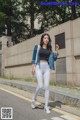 A woman in a black top and white leggings is walking down the street.