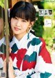 A woman in a kimono standing in front of a window.