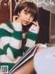 A woman in a green and white striped sweater holding a pencil.