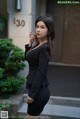 A woman in a black dress smoking a cigarette.