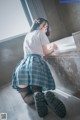 A woman in a school uniform crouching down on the floor.