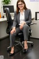 A woman in a business suit sitting on a chair.